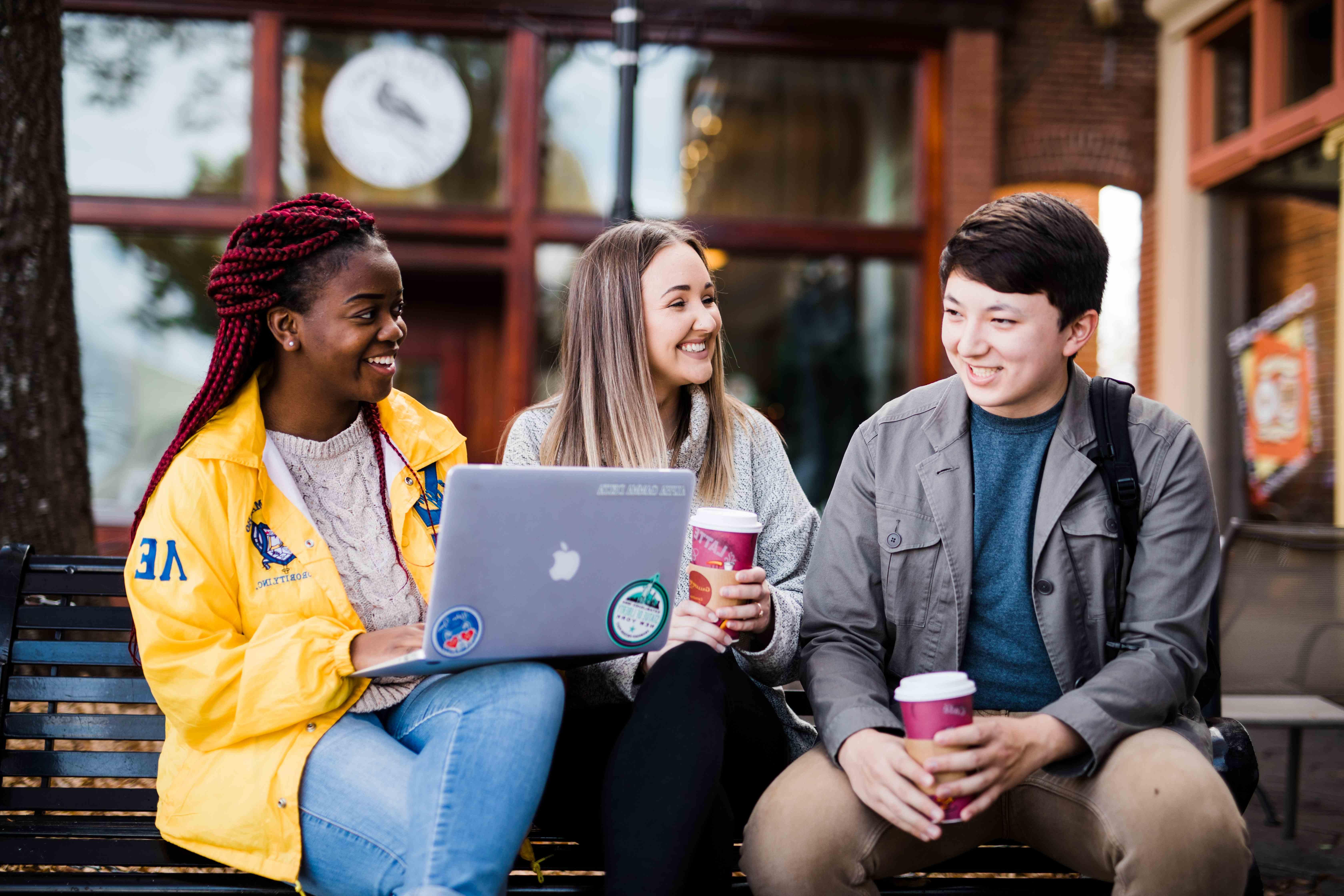 3个学生坐在外面聊天喝咖啡